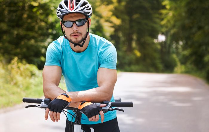 Young man cycling free of hand, wrist and elbow pain on country road.