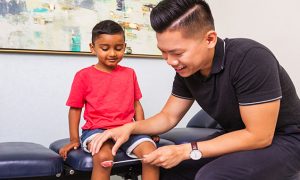 Chiropractor assessing boy's knee