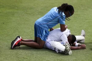 Two soccer players on the soccer field, with one stretching the back of another