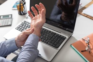 Man suffering from carpal tunnel syndrome holding his wrist in pain.