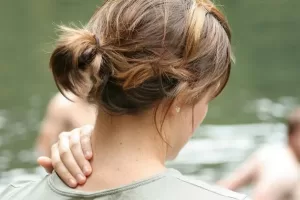 An image of a woman rubbing her neck in pain.